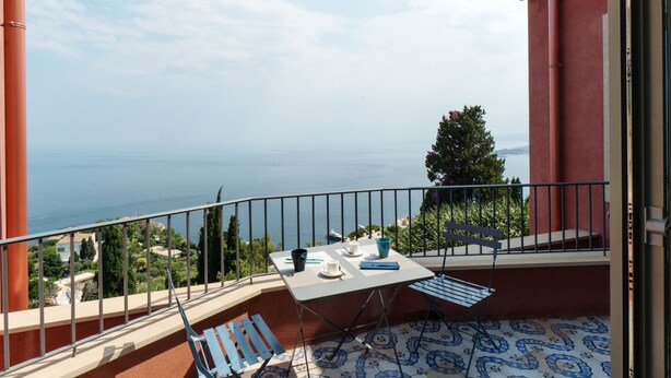 A balcony with a table, chairs, and a view of the sea. - Charming  elegantly  apt in villa near the center but in a very quite area (taormina)