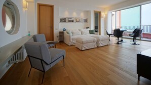 A spacious living area with a large window, a sofa set, a coffee table, and a dining table. - Charming  elegantly  apt in villa near the center but in a very quite area (taormina)