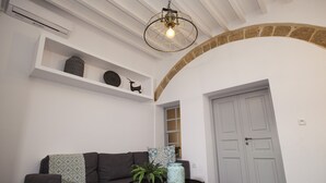 Un salon avec un canapé, une table basse ornée d’une plante, un vase décoratif et une porte blanche.