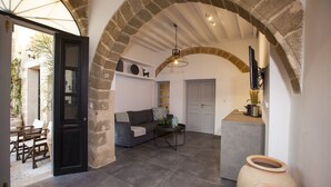 Un salon chaleureux avec une arche en pierre, un canapé, une table basse et un téléviseur fixé au mur.