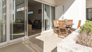A modern outdoor patio with a dining table and chairs, a sofa, and a sliding glass door leading to an interior living space. - 2 bedroom ground floor apartment, located on the award winning Lagos Marina   (Lagos)