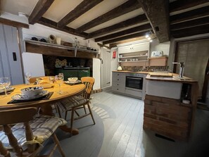 Una cocina acogedora con comedor, vigas de madera y horno empotrado.