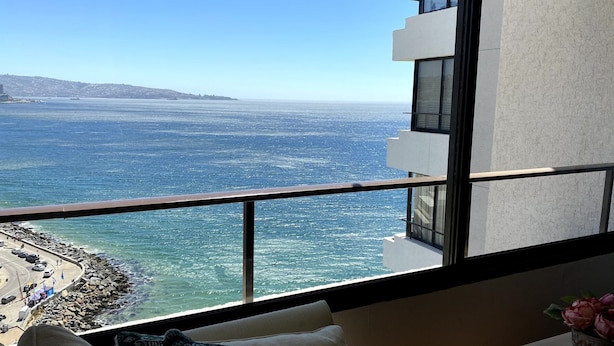 Een balkon met uitzicht op de oceaan en een rotsachtige kustlijn.