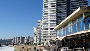 Een strandhotel met meerdere hoge gebouwen, een zandstrand en een helderblauwe lucht.