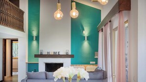 A modern living room with a teal accent wall, a fireplace, and a grey sofa. - Villa with wonderful view and great location. (Las Lagunas de Mijas)