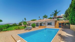 A swimming pool with a tiled deck, a patio area with lounge chairs, and a view of a hillside. - Villa with wonderful view and great location. (Las Lagunas de Mijas)