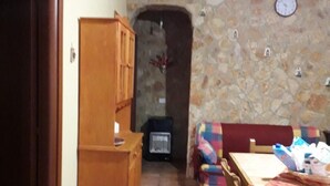 Una sala de estar acogedora con una pared de piedra, un aparador de madera, un sofá y una mesa de comedor.