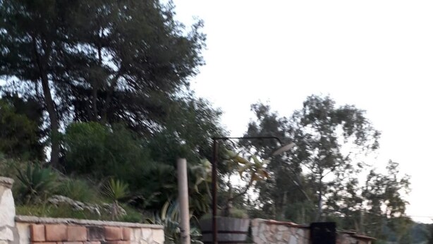 Una zona de cocina al aire libre de piedra con chimenea de ladrillo y un banco de piedra.