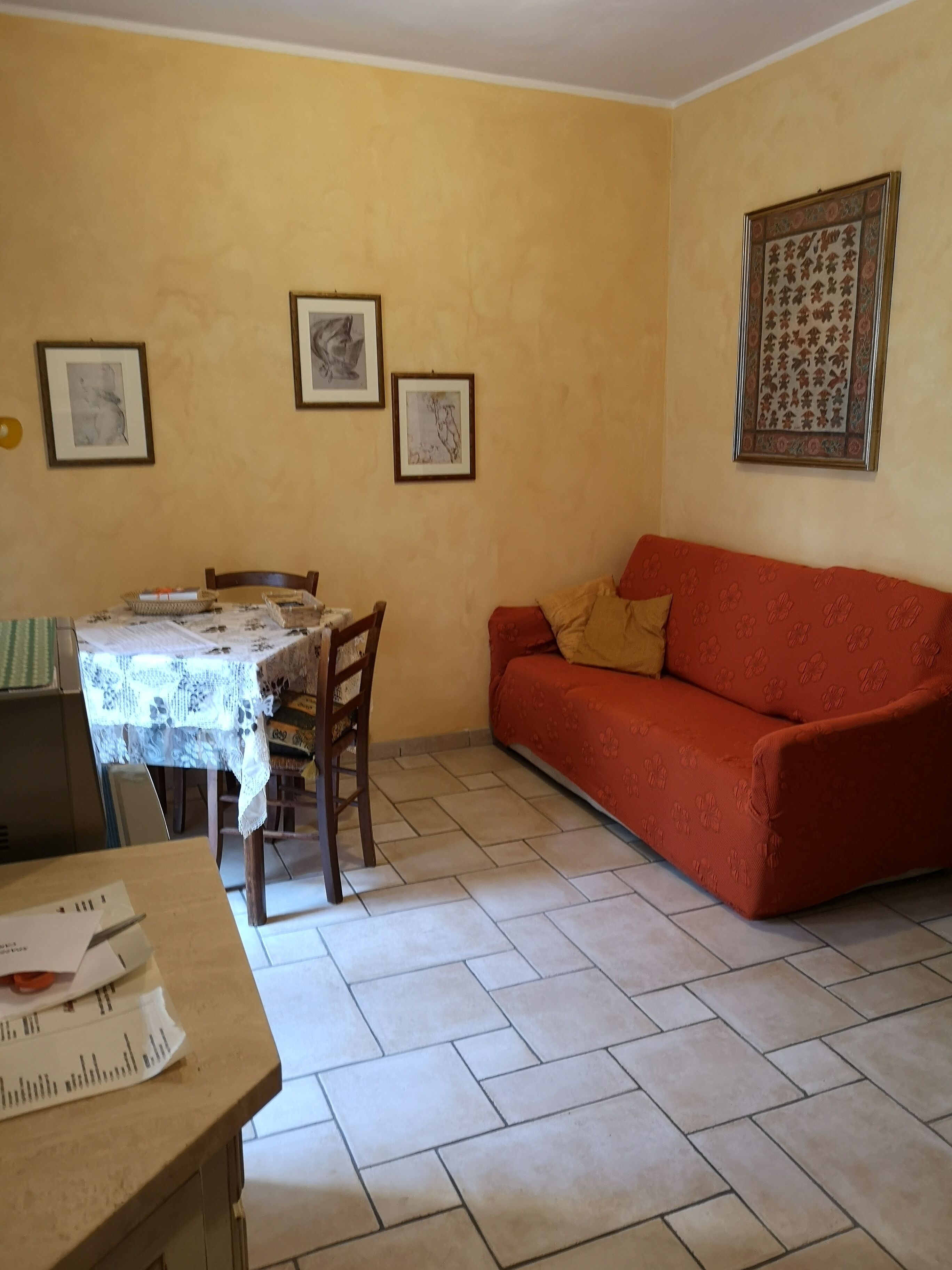 Un salon comprenant une table à manger, un canapé et des tableaux encadrés accrochés aux murs.