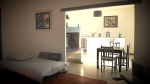 A bedroom with a bed, a desk, and a chair. There is a painting on the wall and a window with a view of the outside. - Self catering Les Rizières + Cottage hunting (Saint-Gilles)
