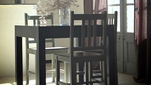 A dining area with a table and chairs, a vase with flowers, and a window with curtains. - Self catering Les Rizières + Cottage hunting (Saint-Gilles)