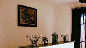A reception desk with a framed painting above it, a small decorative item on the counter, and a window with curtains to the right. - Self catering Les Rizières + Cottage hunting (Saint-Gilles)