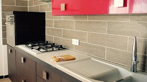 A kitchen with a gas stove, a sink, and a red cabinet. - Self catering Les Rizières + Cottage hunting (Saint-Gilles)