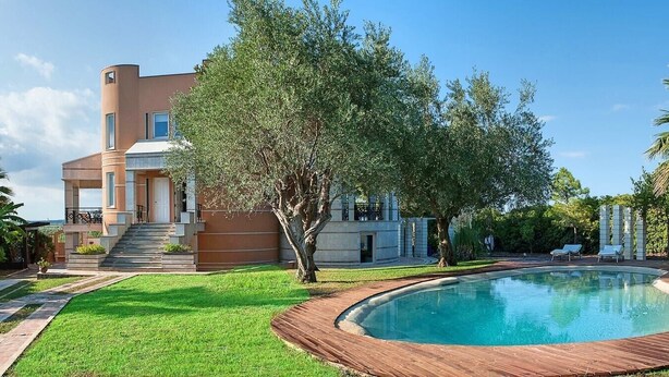 Une maison moderne dotée d’une piscine, d’une pelouse bien entretenue et d’un grand arbre.