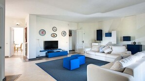Un salon moderne avec un téléviseur à écran plat, un canapé et une table basse.