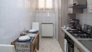 Una cocina compacta con una mesa de comedor, estufa y radiador.