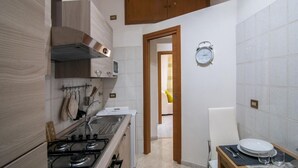 Una cocina compacta con estufa, lavamanos y armarios de madera.