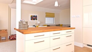 A modern kitchen with a wooden countertop, white cabinets, and pendant lighting. - Stunning beach cottage for the perfect British family holiday with 3 bedrooms (Pevensey Bay)