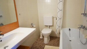 A bathroom with a sink, toilet, bathtub, and shower curtain.