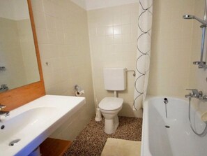 A bathroom with a sink, toilet, bathtub, and shower curtain.