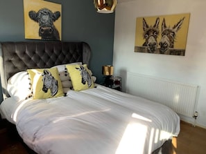 A bedroom with a tufted headboard, a white bedspread, and two zebra-themed pillows. - Boss Places Mathew St 2 Bed duplex 2 bed sleeps 6 (Merseyside)