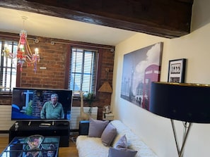 A living room with a television, sofa, and decorative items. - Boss Places Mathew St 2 Bed duplex 2 bed sleeps 6 (Merseyside)
