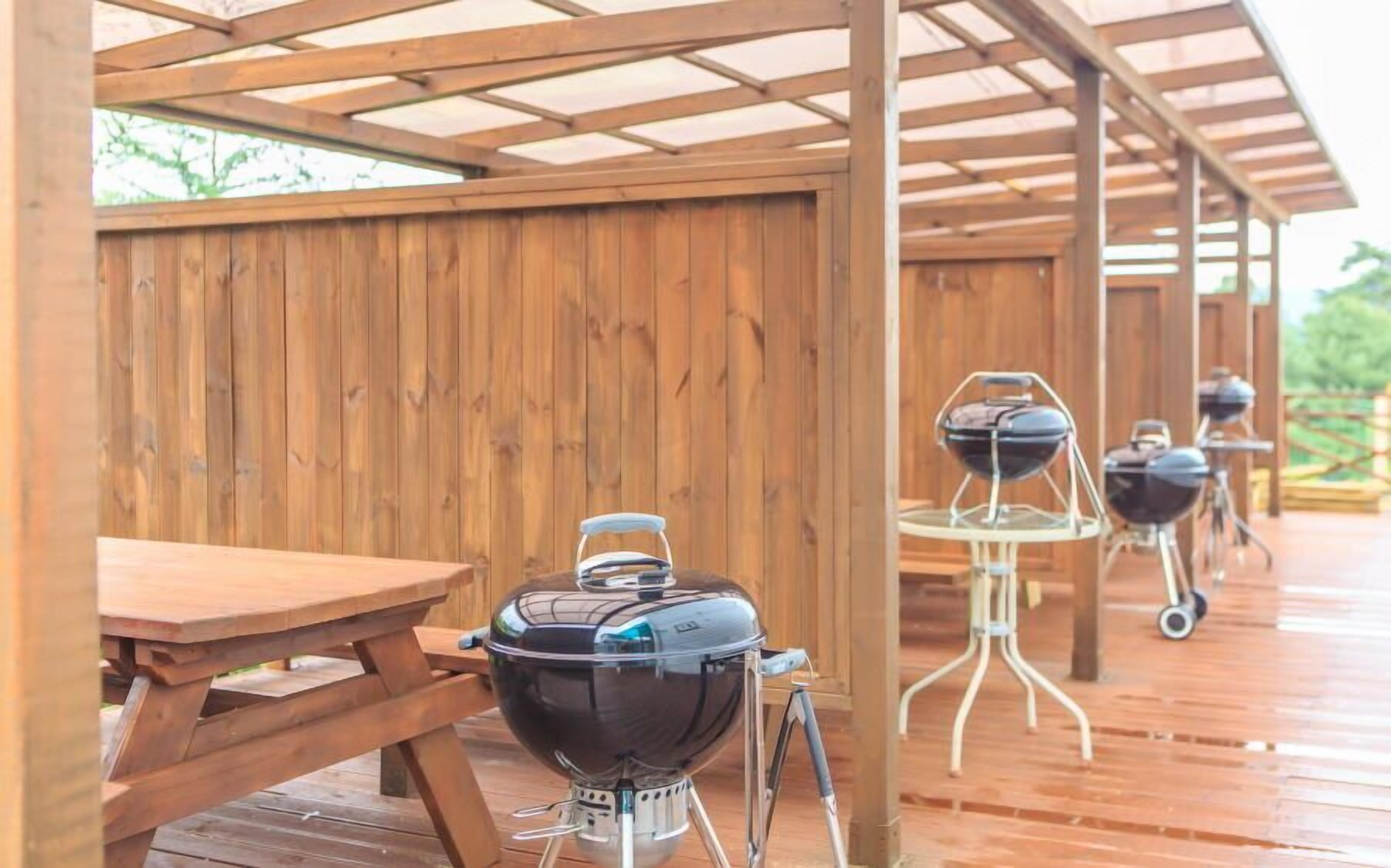 A covered wooden deck with a picnic table and portable grills.