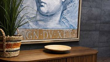 Un área de recepción con un aparador de madera, una obra de arte enmarcada y una planta en maceta.