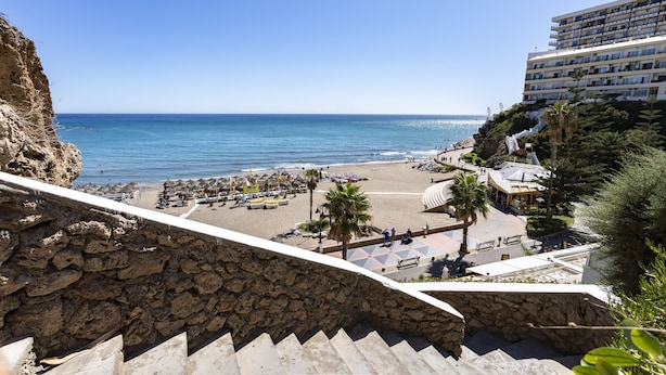 Ein Hotel an der Küste mit Blick auf den Strand, Steinstufen zum Strand und einem Poolbereich.