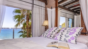 Ein Schlafzimmer mit einem großen Bett, Meerblick und einer Palme davor.