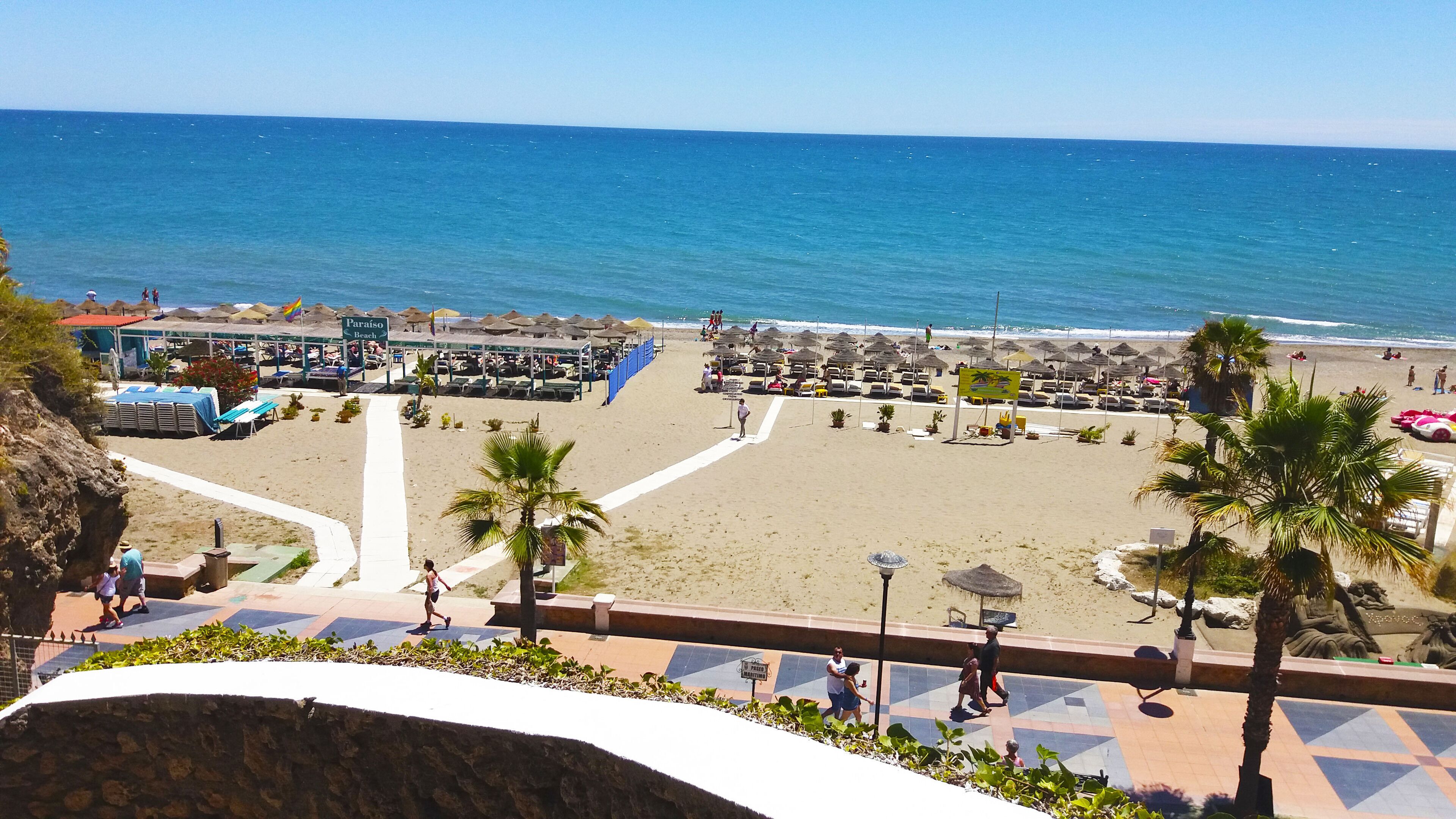 Une plage avec des parasols, des chaises longues et un panneau indiquant « Plage Paraíso ».