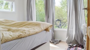 Une chambre à coucher avec un lit, une fenêtre et des rideaux.