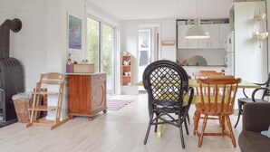 Une cuisine spacieuse avec des meubles blancs, un coin repas doté de chaises en bois et une grande fenêtre laissant entrer la lumière naturelle.
