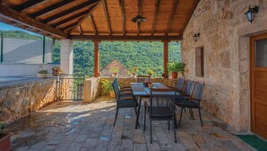 A covered outdoor seating area with stone walls, a wooden ceiling, and a view of a mountainous landscape. - Stunning home in Krivodol (Krivodol)