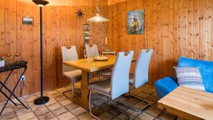 Een kamer met houten lambrisering, een eettafel, stoelen, een blauwe bank, een vloerlamp en een ster-decoratie.