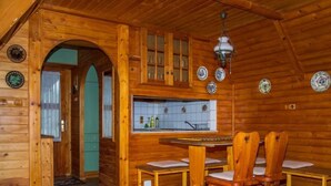 L’intérieur d’un chalet en bois comprend un coin repas, des murs en bois et une cuisine avec un dosseret carrelé.