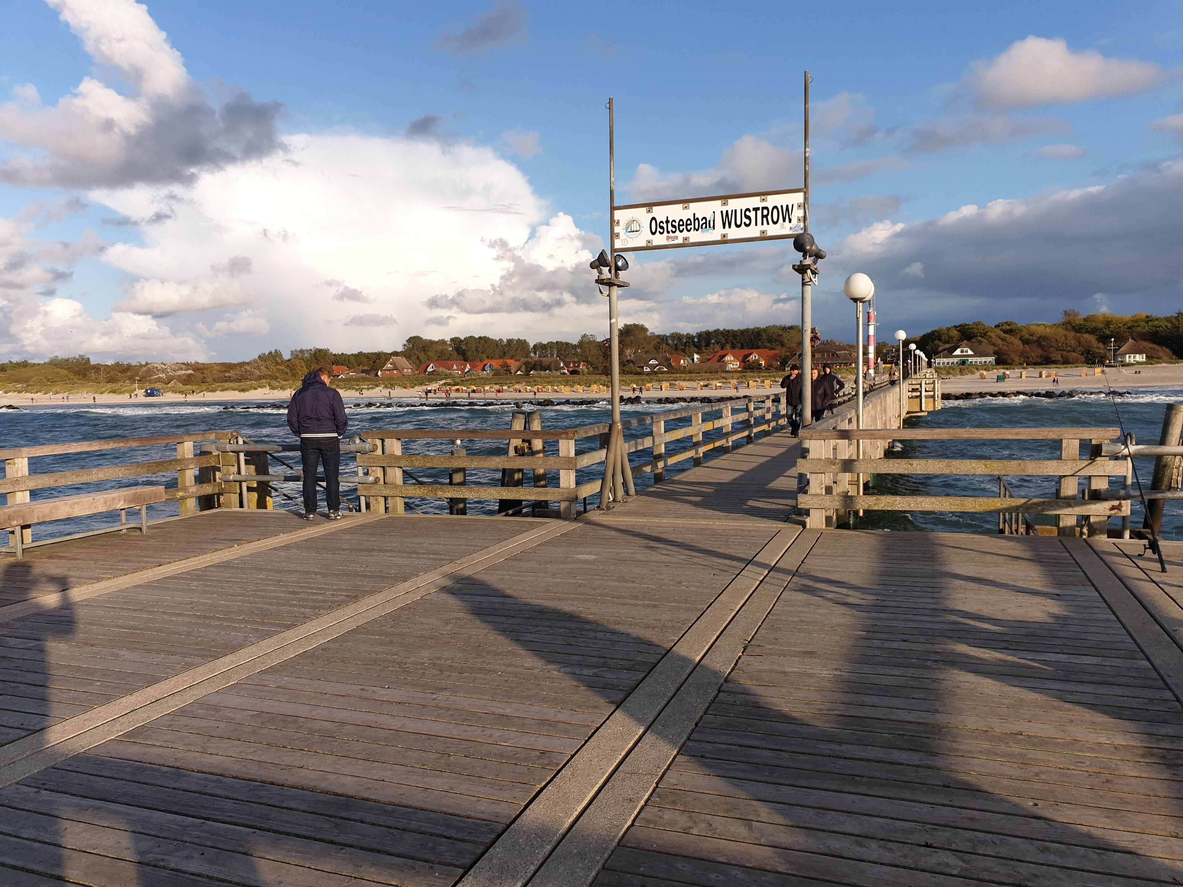 A wooden pier with a sign reading 'Ostseebad Wustrow' leading to a beach.