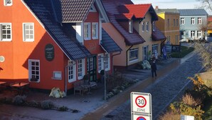 Rivissä värikkäitä rakennuksia, mukulakivikatu, liikennemerkki, joka osoittaa nopeusrajoituksen 30 km/h, ja ulkona olevia istumapaikkoja.
