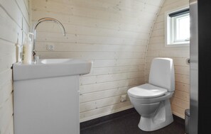 Une petite salle de bain compacte, avec un lavabo blanc, des toilettes et une fenêtre qui laisse entrer la lumière naturelle.