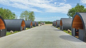 Een rij caravanaccommodaties met een verharde looppad die naar een centraal punt leidt.
