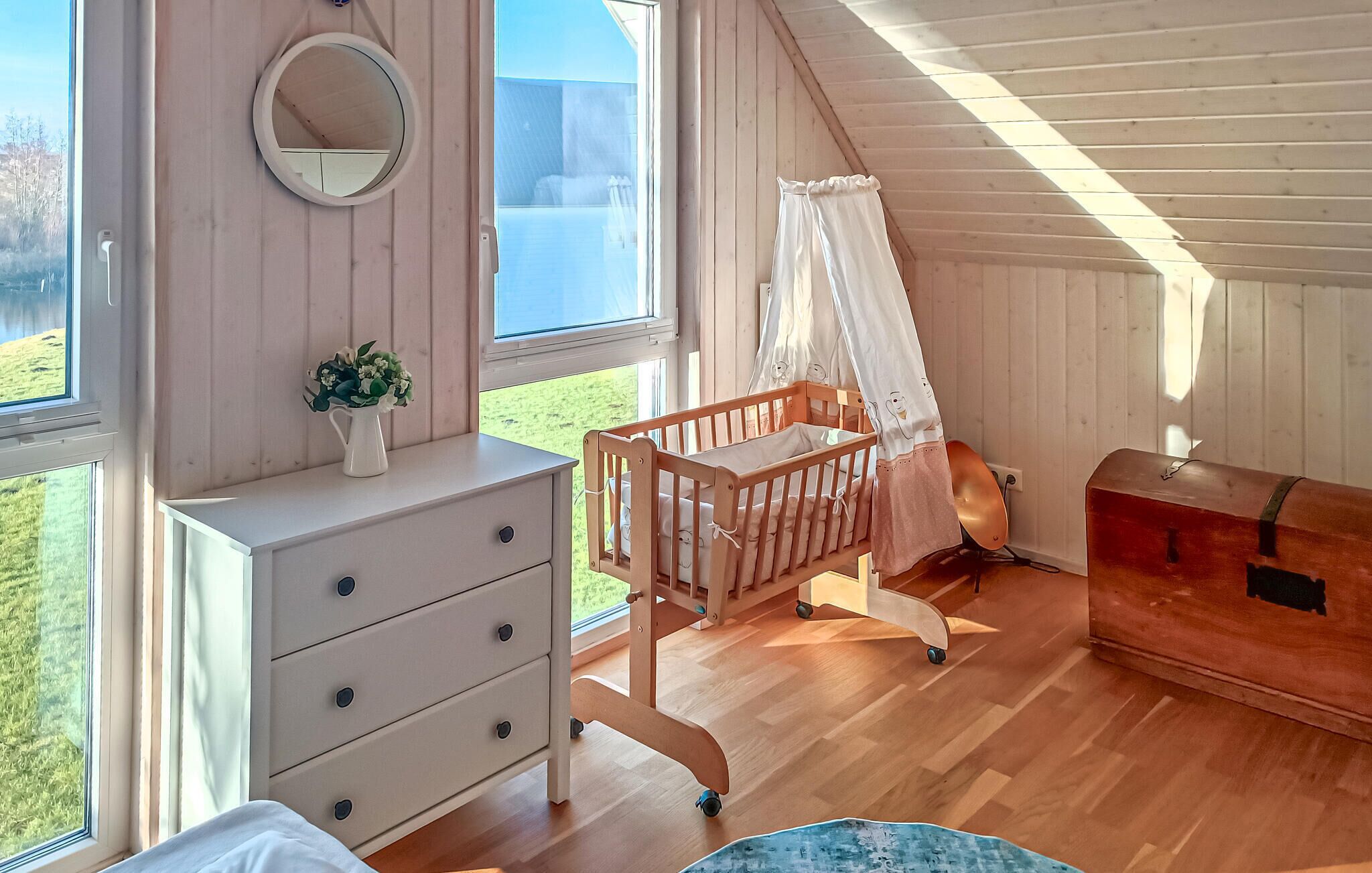 A cozy attic bedroom with a crib, a dresser, and a chest of drawers.