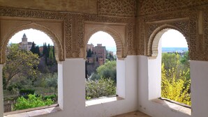 Une pièce dotée de trois fenêtres en arc donnant sur un bâtiment historique et un jardin.