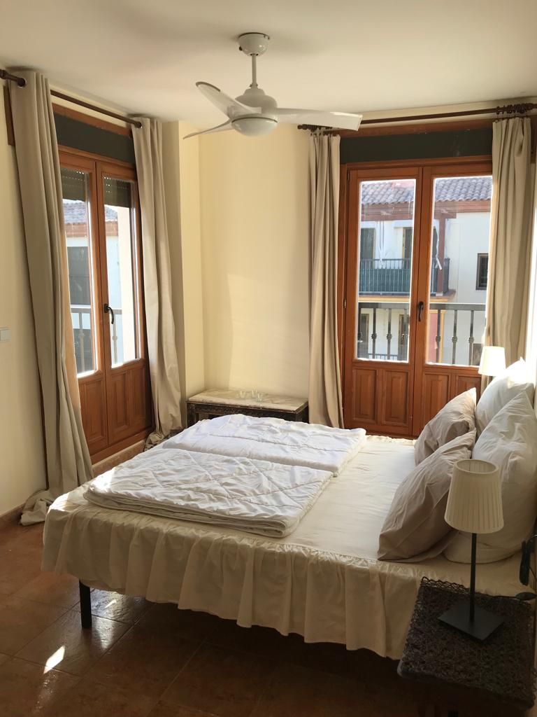 Ein Schlafzimmer mit einem Bett, einem Nachttisch, einer Lampe und einem Deckenventilator.
