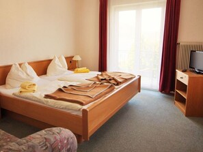 Ein Hotelzimmer mit Bett, Fernseher, Schreibtisch und einem Fenster mit Vorhängen.