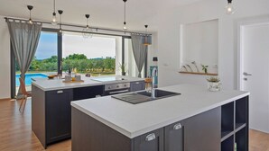 Eine moderne Küche mit einer großen Kochinsel, integrierten Geräten und Blick auf einen Pool.