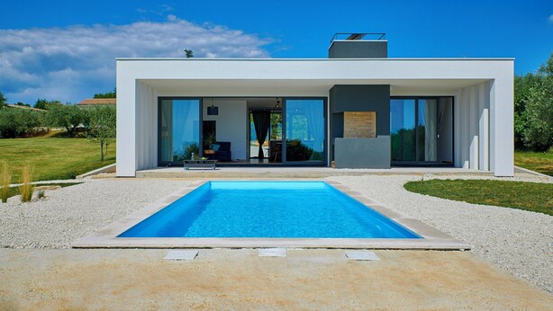 Ein modernes Haus mit Swimmingpool, großen Glasfenstern und einem Garten.