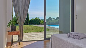 Ein Schlafzimmer mit Blick auf einen Swimmingpool und Grünflächen.