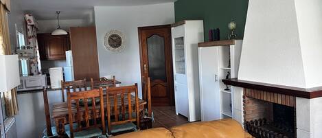Un salon avec un canapé en cuir, un coin repas avec des chaises en bois, une cuisine équipée d’un four à micro-ondes et d’un réfrigérateur, et une cheminée.