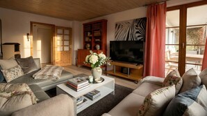 A living room with a sofa, coffee table, bookshelf, TV, and a door. - Dreamland—plenty of space for up to 5 guests (Überlingen, Baden-Württemberg, Germany)