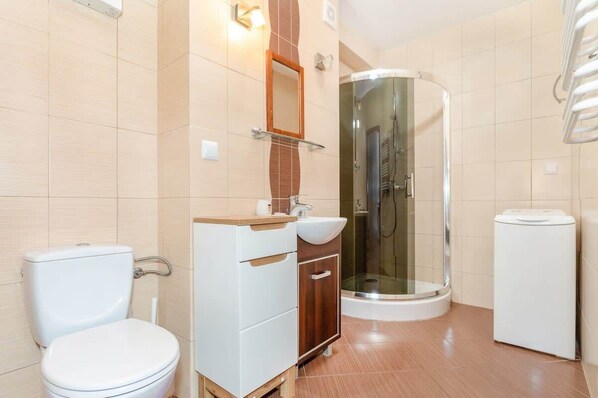 Un baño moderno con inodoro, lavamanos, tocador y ducha con mampara de vidrio.